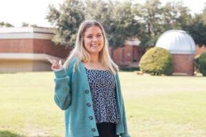 Sydney Smith smiles in front of Newman-Richardson Science Center at HSU.